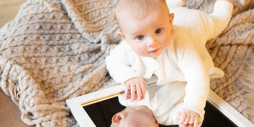 Babyshooting Outfit Baby spielt im Babyshooting mit dem Spiegel
