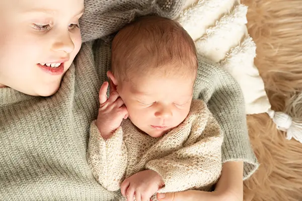 Bruder freut sich über Newborn im Shooting Newborn