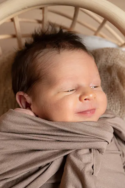 Newborn Shooting: Lächelndes Newborn in der Wiege