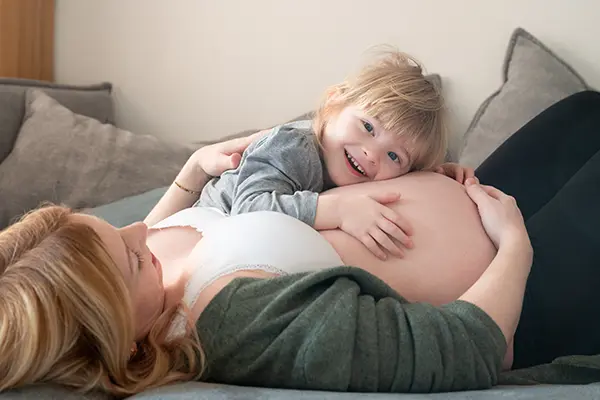 Mama kuschelt mit Tochter beim Schwangerschafts-Fotoshooting