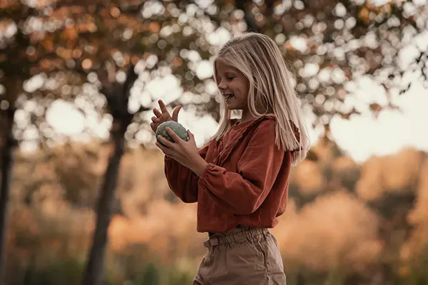 Kinderfotograf fotografiert Kind mit Kürbis im Herbst