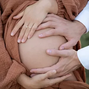 Hände auf dem Bauch im Babybauch Fotoshooting draußen