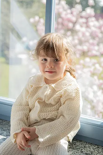Kind sitzt im Kindershooting am Fenster