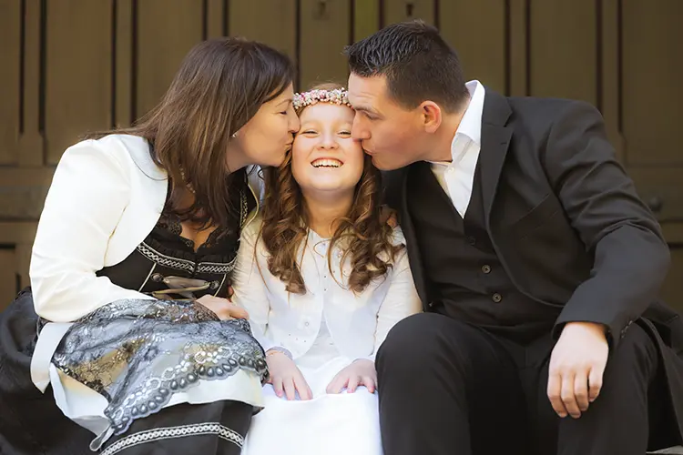 Eltern küssen Kind im Kommunion Fotoshooting München
