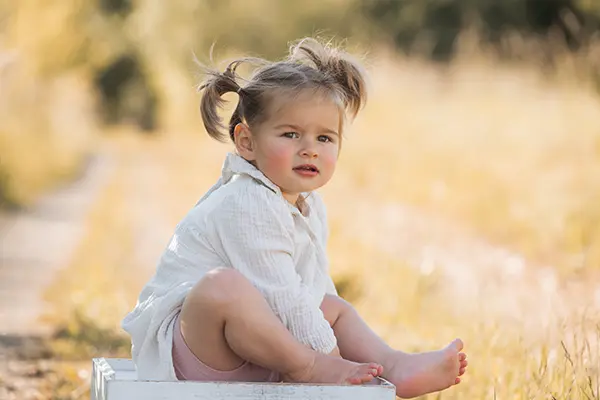 Familienfotografie Mädchen sitzt auf Kiste und freut sich