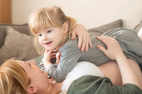 Kind freut sich im Babybauch Shooting mit Kindern