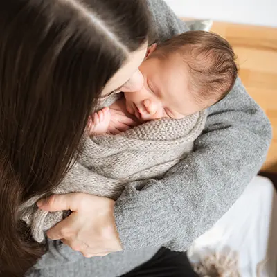 Mutter hält Neugeborenes auf dem Arm im Neugeborenen Fotoshooting München