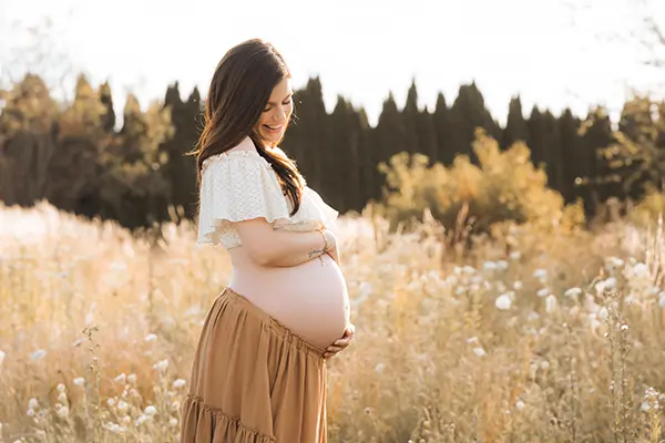 Schwangere auf der Wiese im Babybauch Shooting München