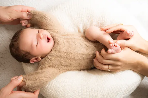 Eltern halten ihr Newborn im Neugeborenenshooting in München an den Händen