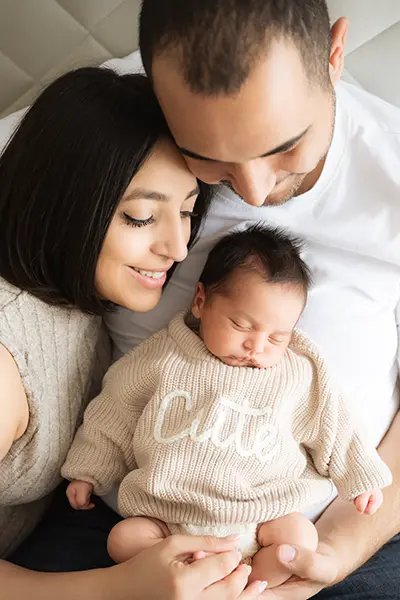 Junge Familie schaut ihr Neugeborenes verliebt an