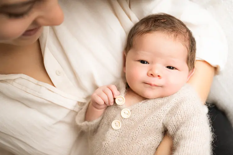 Mom cuddles with newborn in newborn photoshoot