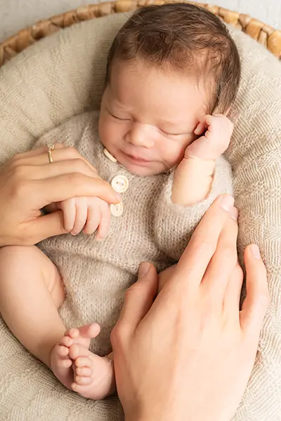 Neugeborenenfotoshooting München Baby liegt gemütlich im Korb mit Händen