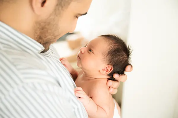 Neugeborenes schaut den Papa interessiert an