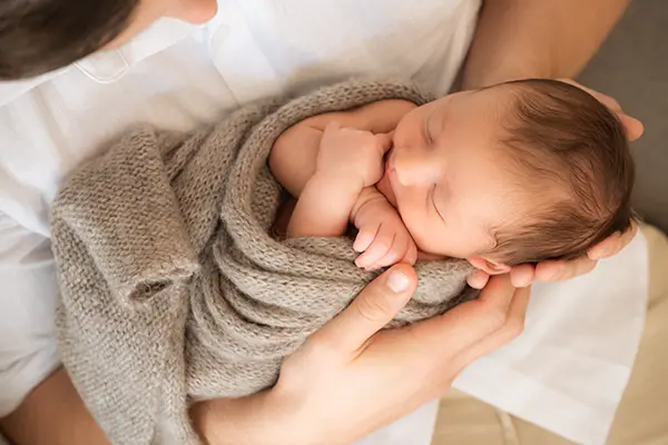 Vater hält Baby im Neugeborenen Shooting München auf dem Schoss