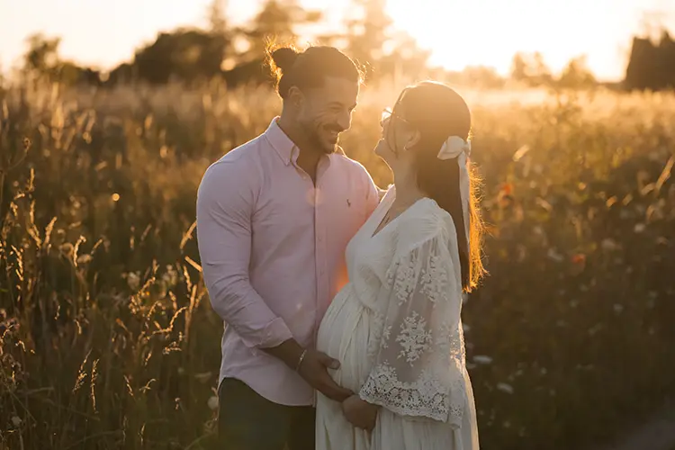 Verliebtes Paar im Sonnenuntergang auf der Wiese im Outdoor Schwangerschaft Fotoshooting