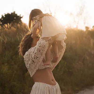 Mutter hält ihr Kind im Gegenlicht im Familien Fotoshooting