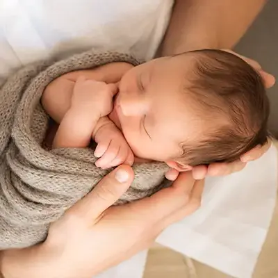 Vater hält Baby im Neugeborenen Shooting München auf dem Schoss