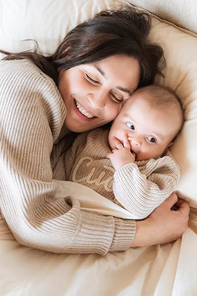 Mama kuschelt mit ihrem Baby im Bett in der Babyfotografie
